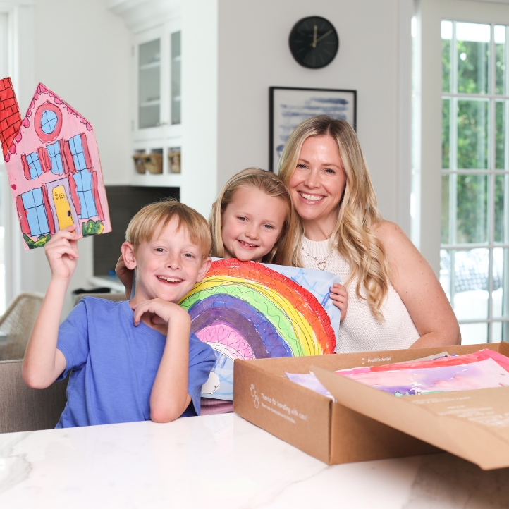 Family sorting children's artwork at a table with Artkive box