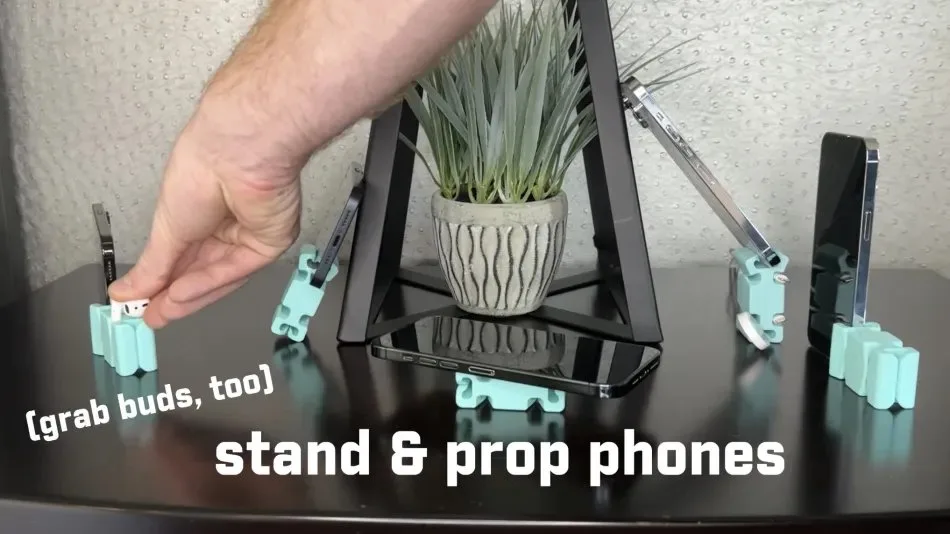 Person using CordBrick to prop up phones and hold earbuds on a table