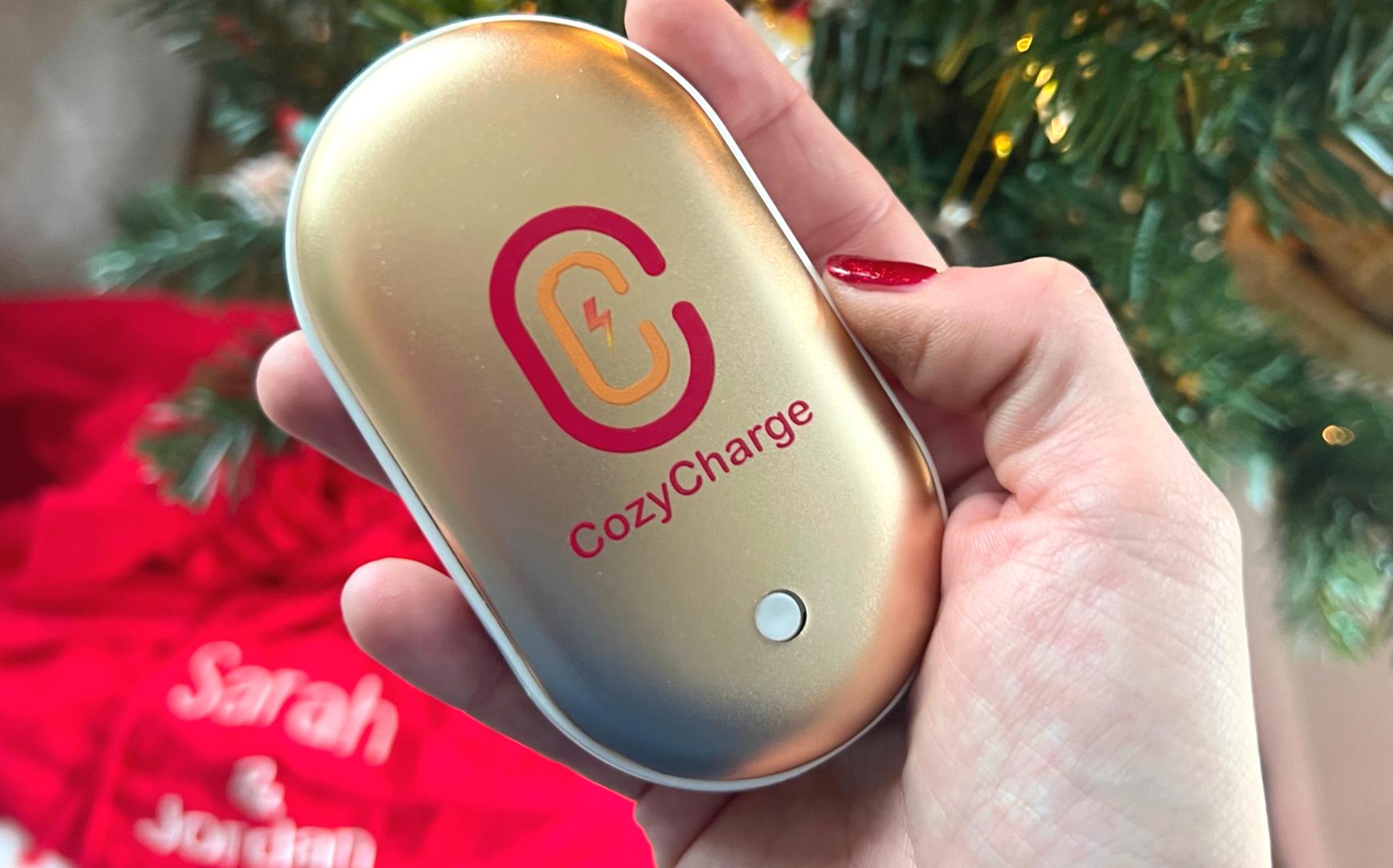 CozyCharge held in hand in front of a Christmas tree