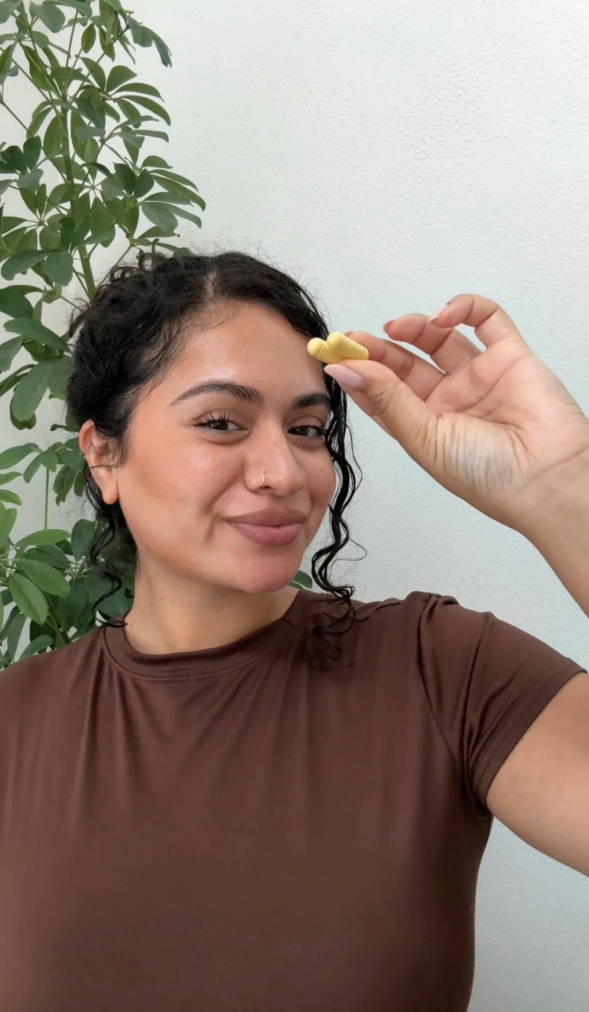 Person smiling and holding an Emma capsule between their fingers