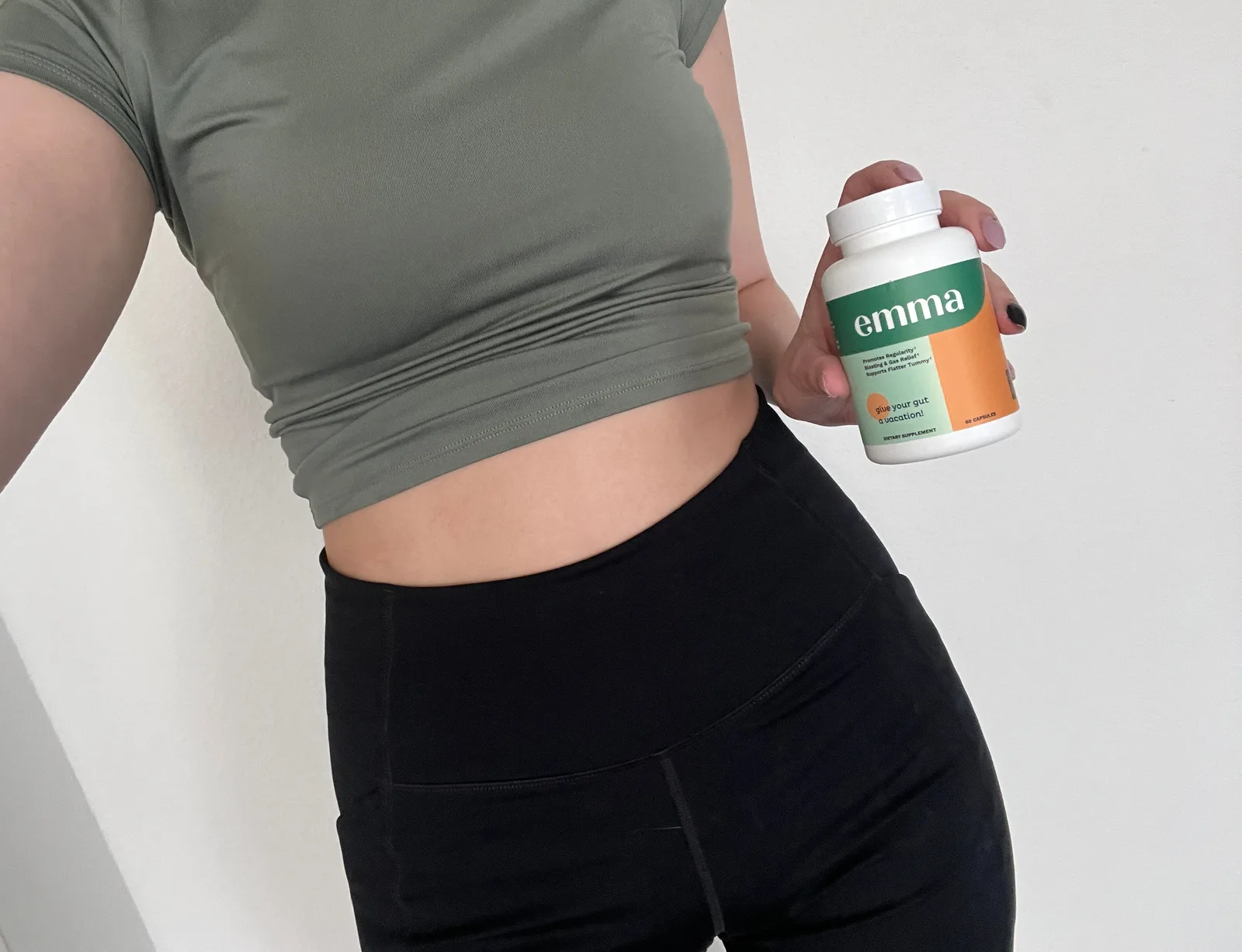 Person holding Emma supplement bottle in front of their torso