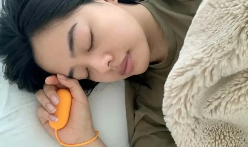 Person lying in bed holding the Chill Pill device while sleeping