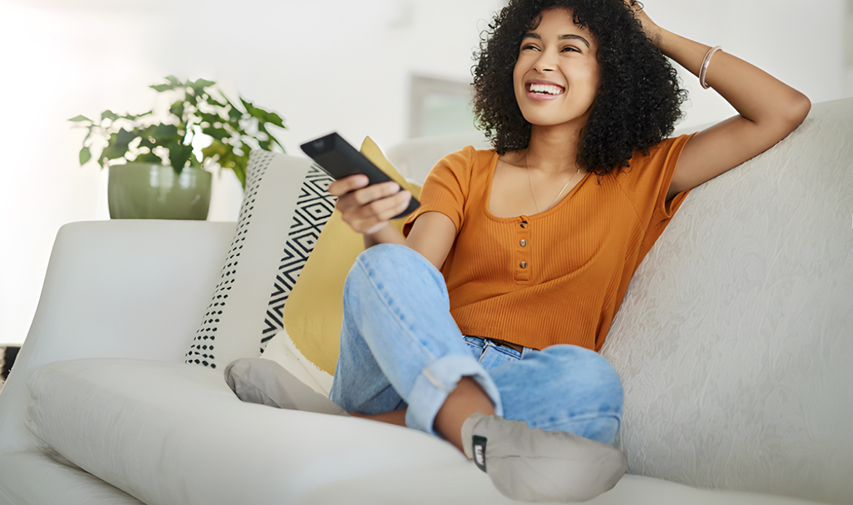 Person relaxing on couch wearing FEETS foot peel mask booties