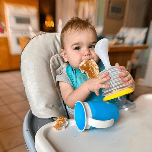 Baby in high chair holding LifeVac device