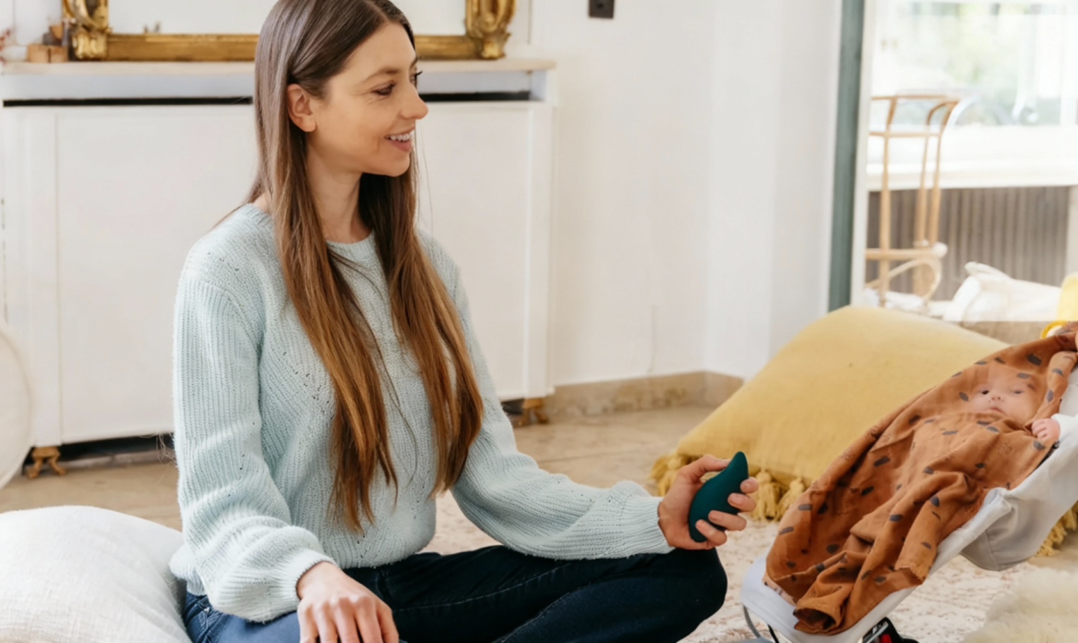 Woman sitting cross-legged on the floor holding Moonbird and smiling at a child