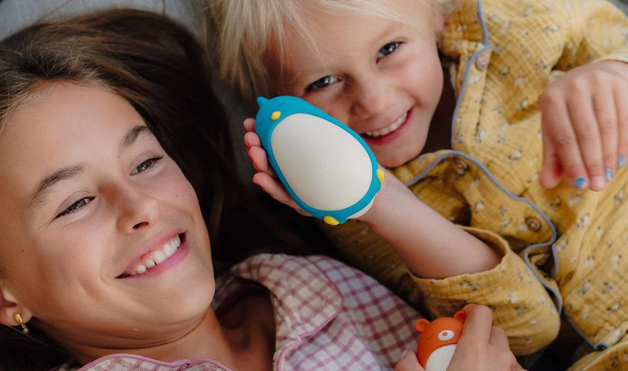 Two children lying down, one holding Moonbuddy