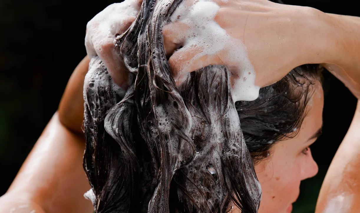 Person washing their hair with soap and water in the shower
