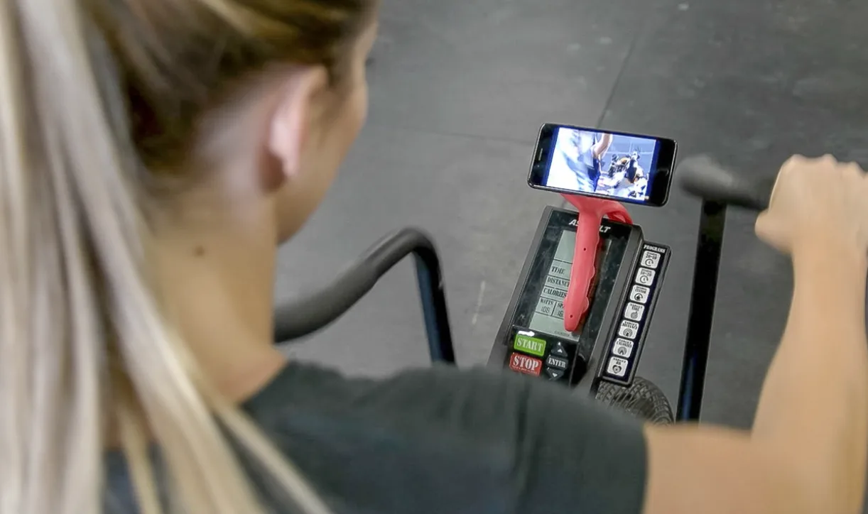 Tenikle holding a phone on exercise equipment during a workout