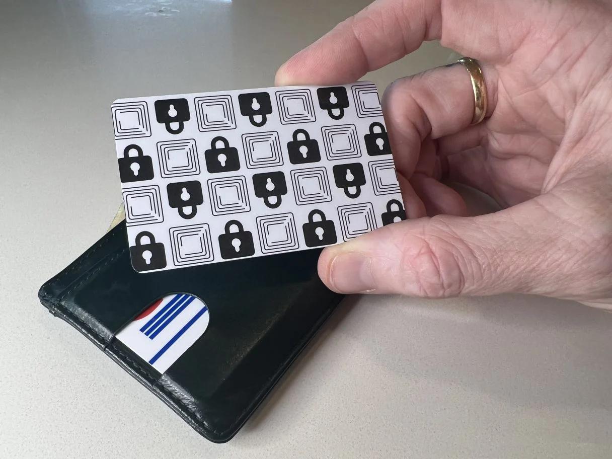 Wallet Defender card held above a wallet with cards inside