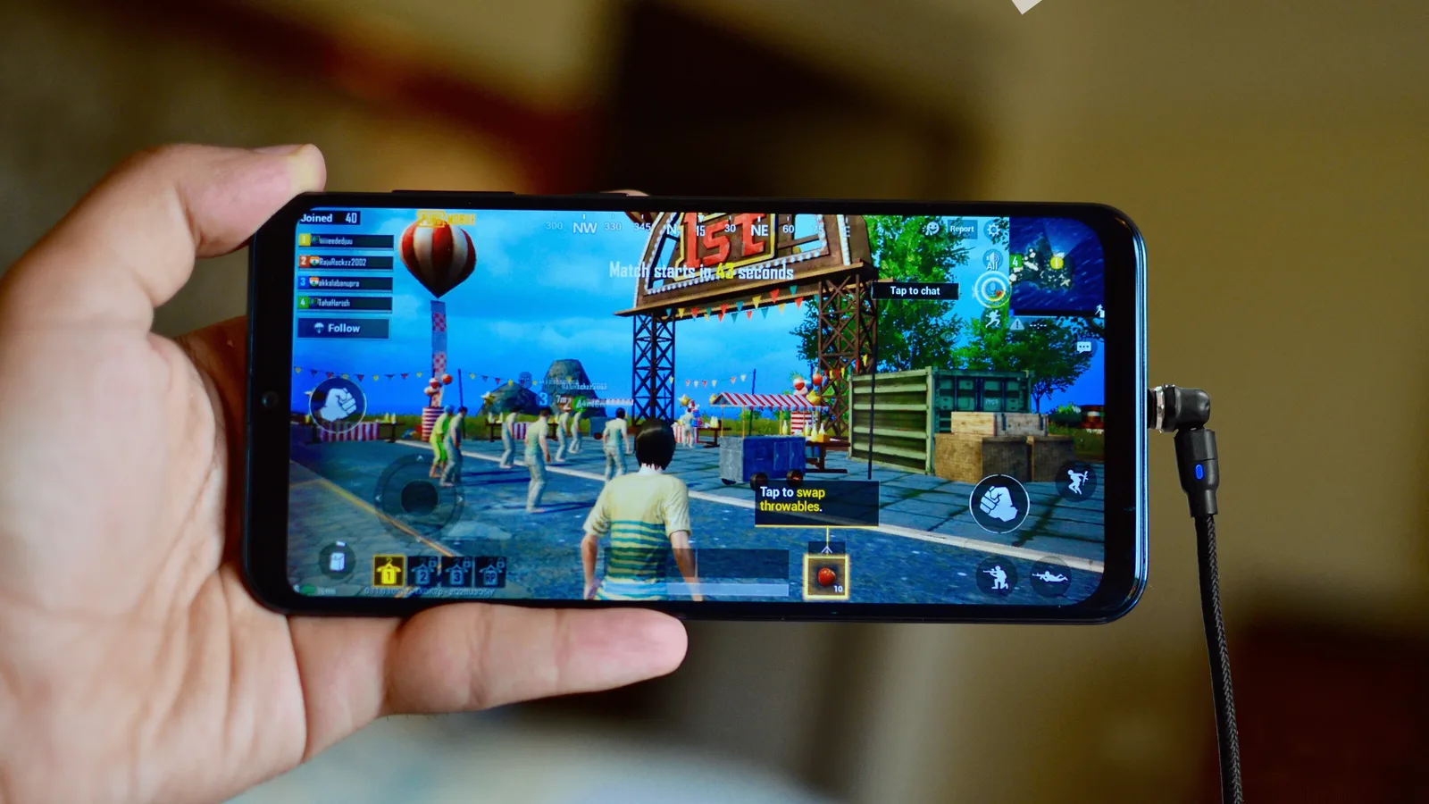 Hand holding a phone mid-game while the Whippy Charge cable stays connected off to the side