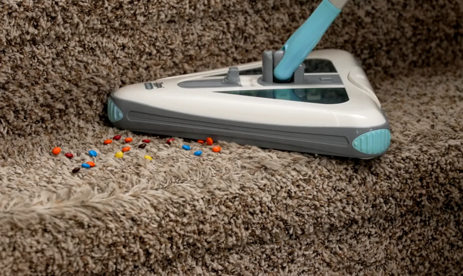 Sweeper picking up small colorful debris on a carpeted staircase